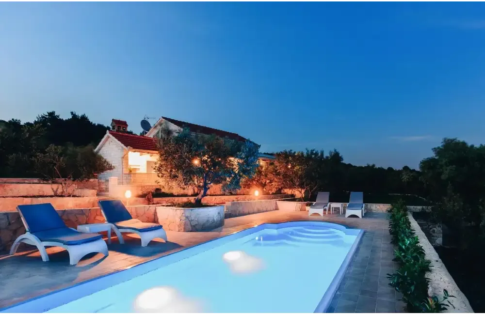 Glasfiberpool Haiti med avrundad trappa vid trädgårdspool i skymning